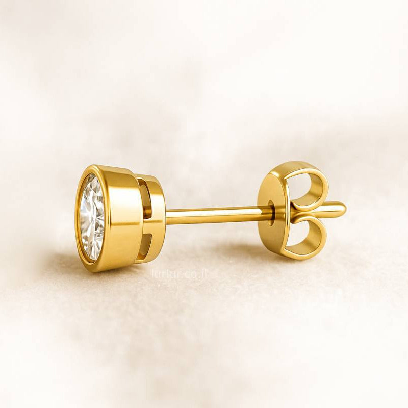 Gold earring with a clear gemstone on a beige background