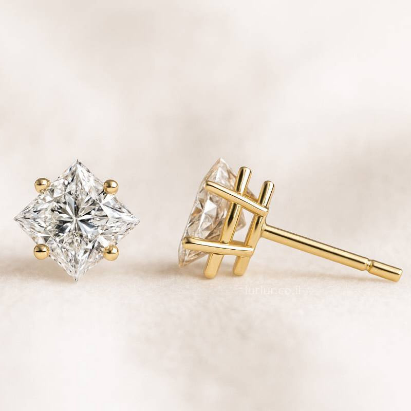 Two diamond stud earrings on a light beige background