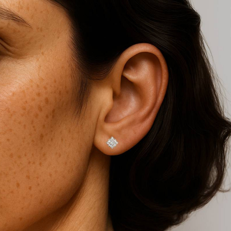 Close-up of a woman's face wearing a diamond earring against a neutral background