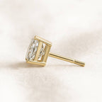 Gold earring with a diamond on a light beige background