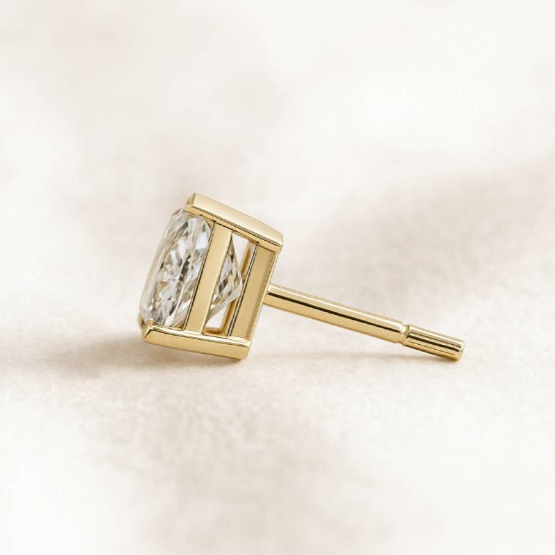 Gold earring with a diamond on a light beige background