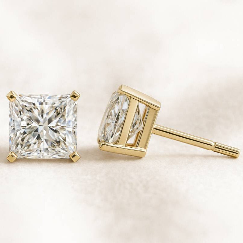 Gold diamond stud earrings on a light background