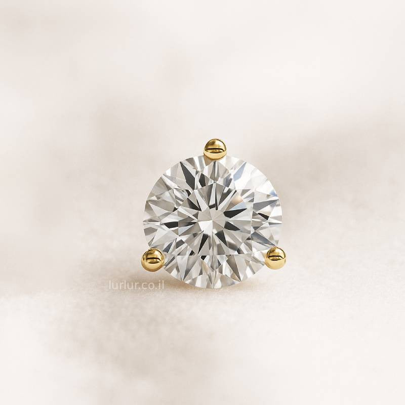 Round diamond in a gold setting on a light beige background