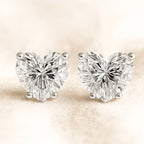 Heart-shaped diamond earrings on a beige background