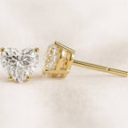 Gold diamond earrings on a light beige background