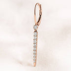 Rose gold hoop earring with clear gemstones on a light pink background
