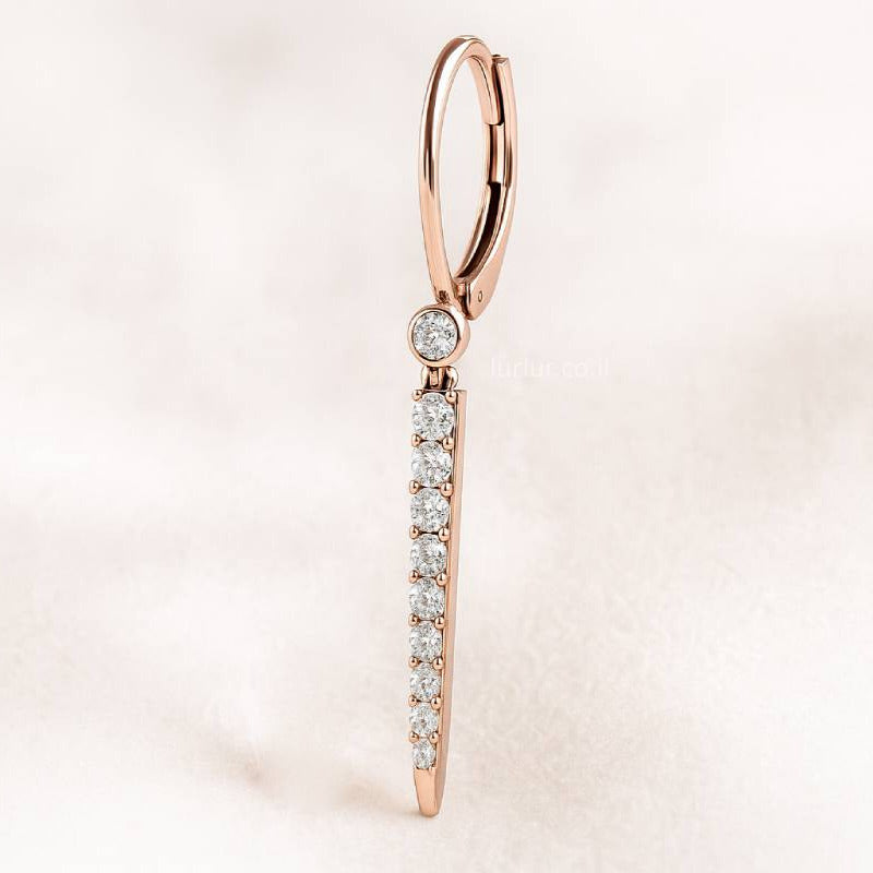 Rose gold hoop earring with clear gemstones on a light pink background