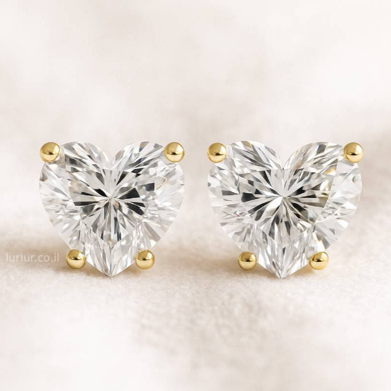 Heart-shaped diamond earrings on a light beige background