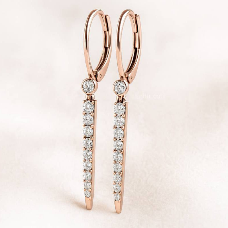 Rose gold earrings with clear gemstones on a light pink background