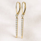 Gold earrings with diamond accents on a light pink background