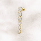 Gold earring with clear gemstones on a light pink background