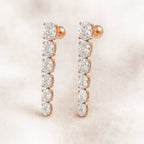 Rose gold earrings with clear gemstones on a soft pink background