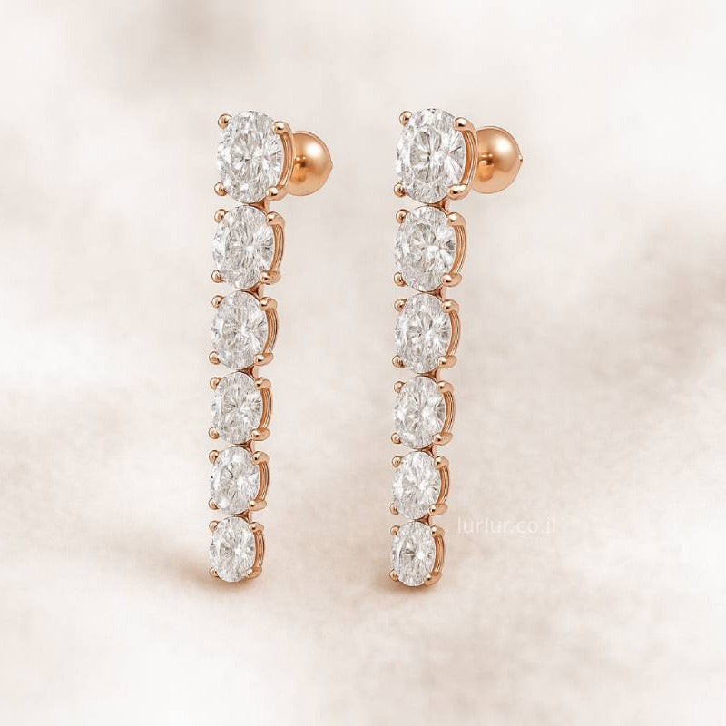 Rose gold earrings with clear gemstones on a soft pink background