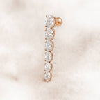 Rose gold earring with clear gemstones on a soft pink background