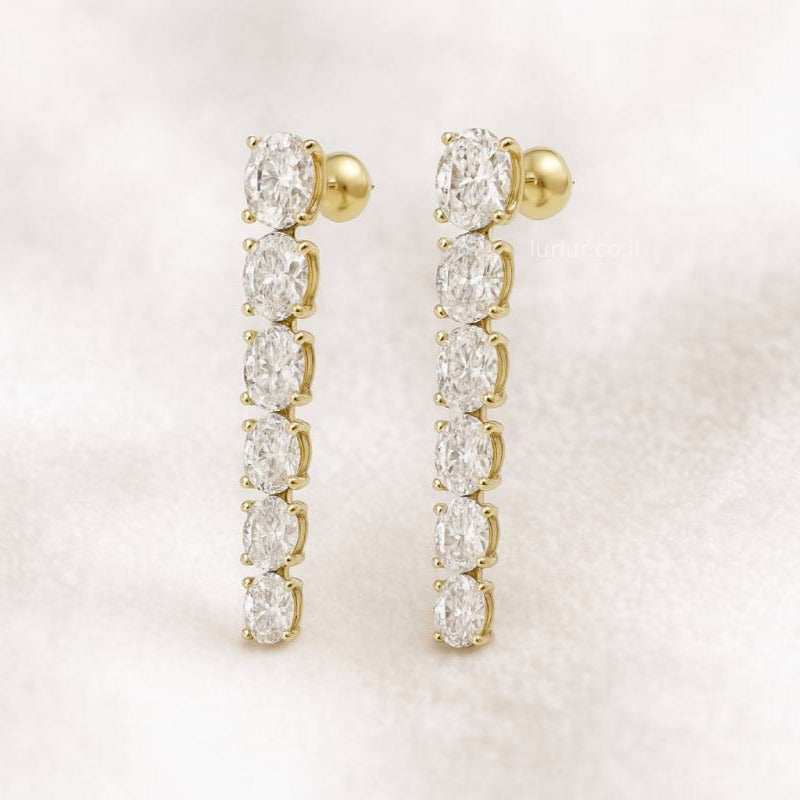 Gold earrings with clear gemstones on a light pink background
