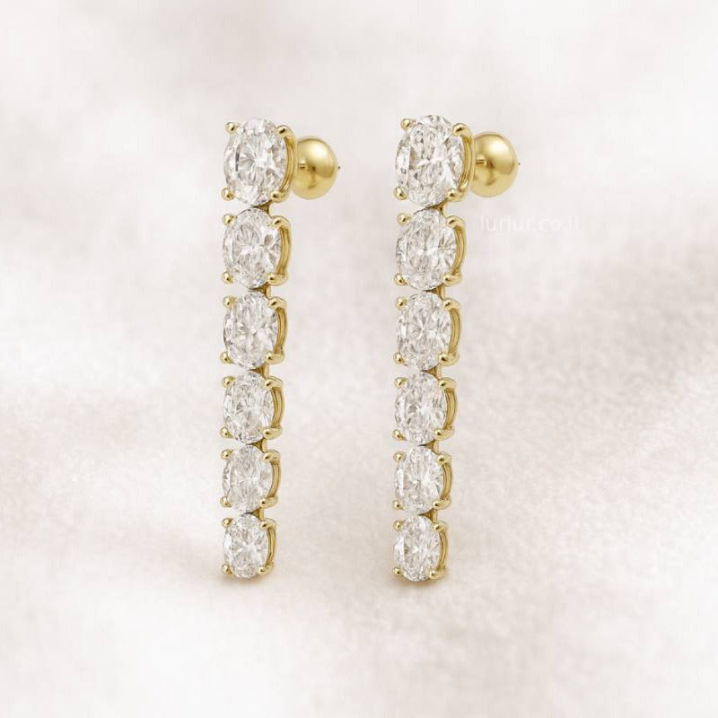 Gold earrings with clear gemstones on a light pink background