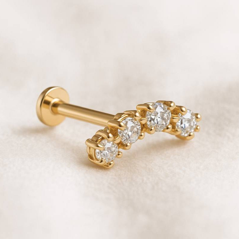 Gold earrings with embedded diamonds on a beige background