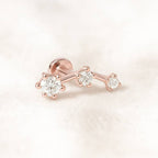 Rose gold earring with three diamonds on a light pink background