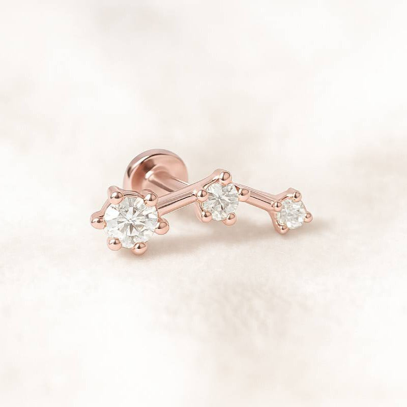Rose gold earring with three diamonds on a light pink background
