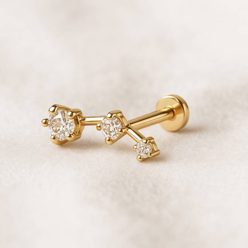 Gold earring with clear gemstones on a light beige background