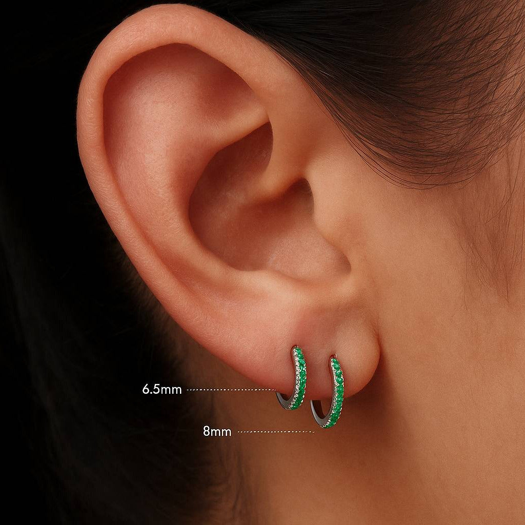 Close-up of an ear wearing green hoop earrings with size measurements.