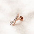 Rose gold earring with clear gemstones on a light beige background