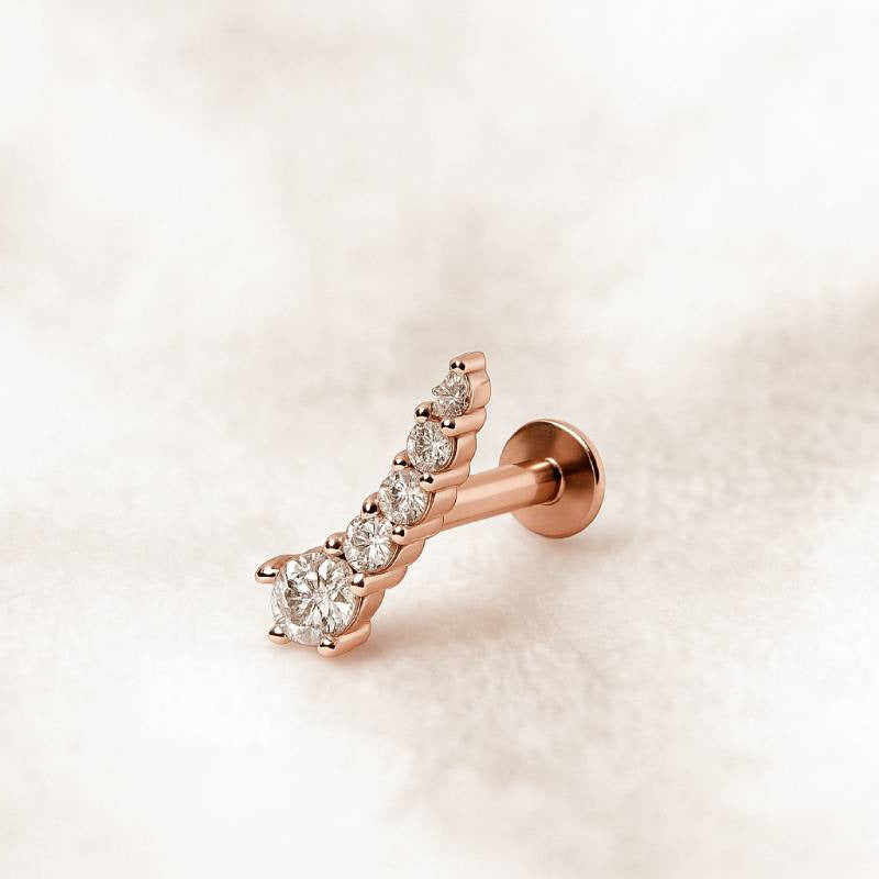 Rose gold earring with clear gemstones on a light beige background