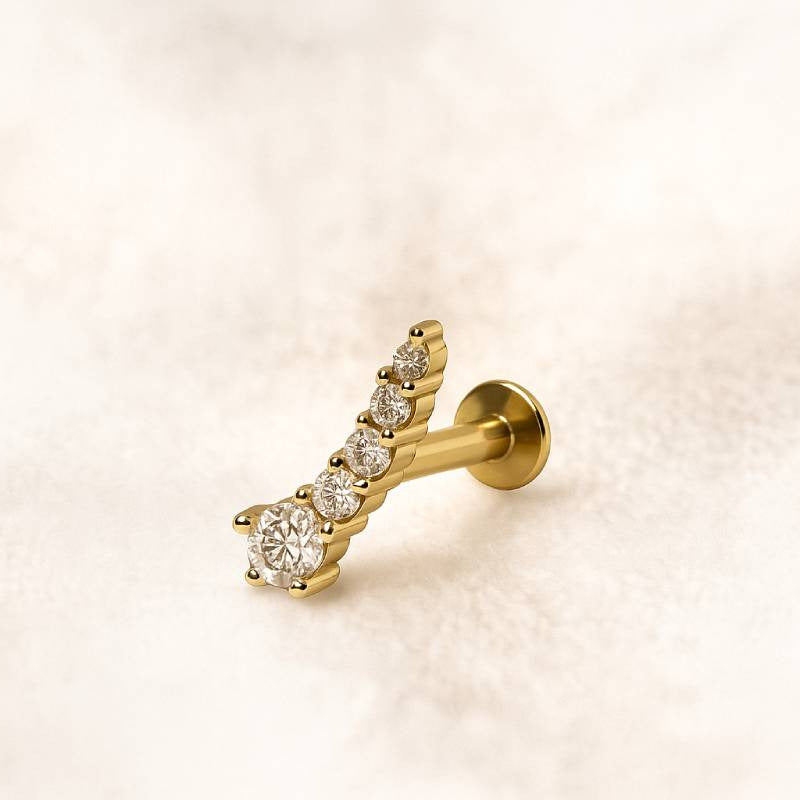 Gold earring with diamonds on a light beige background