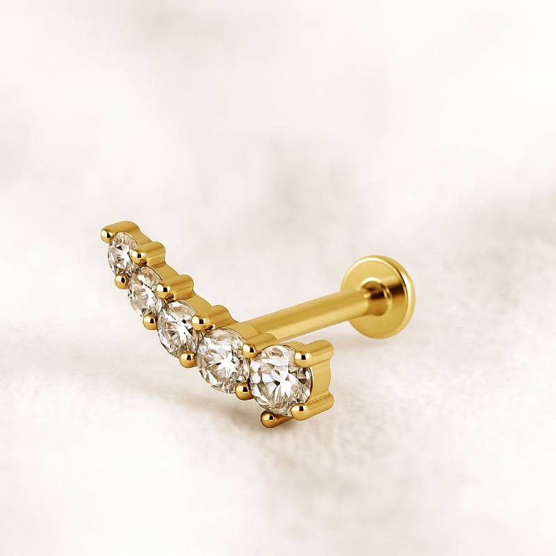 Gold earring with clear gemstones on a light beige background