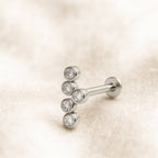 Silver stud earring with clear gemstones on a beige textured background