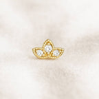 Gold earring with three circular gemstones on a light beige background