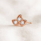 Rose gold butterfly earring with diamonds on a light beige background