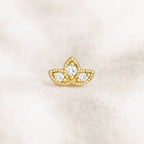 Gold earring with three circular gemstones on a light beige background