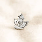 leaf-shaped earring with embedded diamonds on a beige background