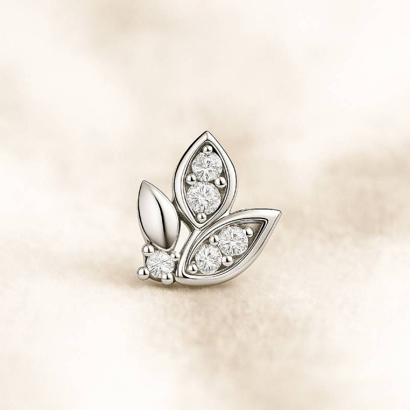 leaf-shaped earring with embedded diamonds on a beige background