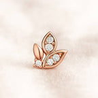 Rose gold leaf-shaped earring with diamonds on a soft pink background