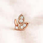Rose gold leaf-shaped earring with diamonds on a soft pink background