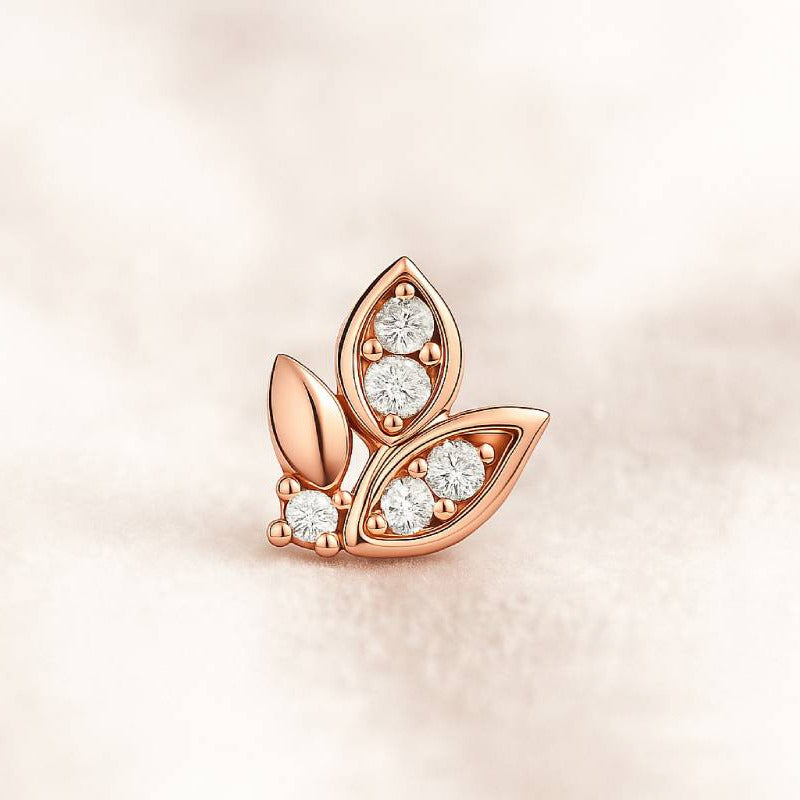 Rose gold leaf-shaped earring with diamonds on a soft pink background
