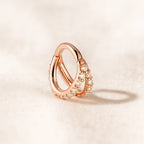 Rose gold ring with pearl accents on a light beige background