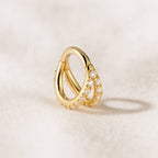 Gold earring with small pearls on a beige background