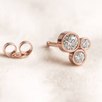 Rose gold earrings with clear gemstones on a light beige background