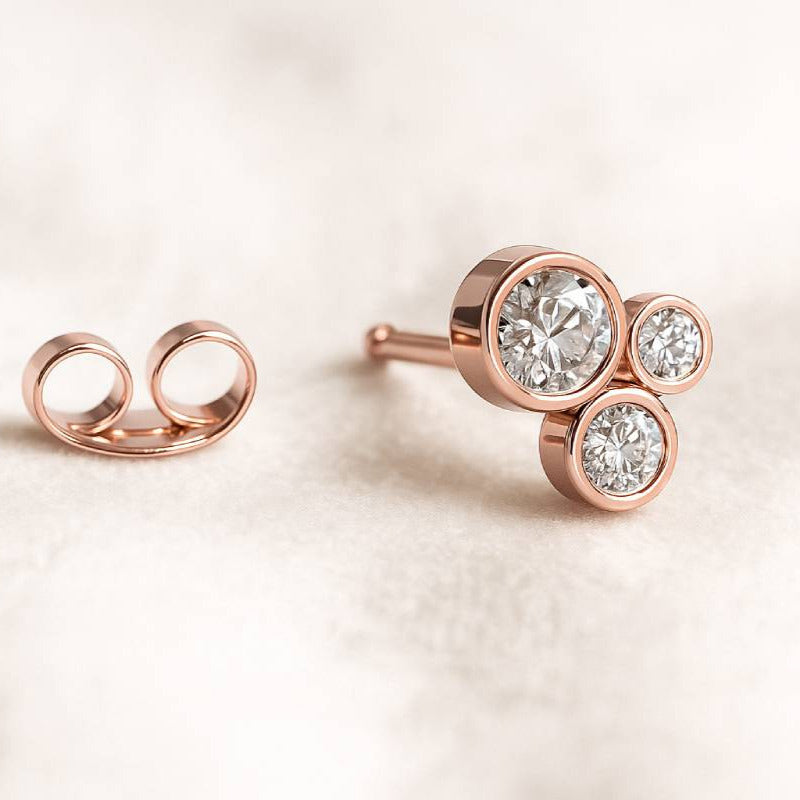 Rose gold earrings with clear gemstones on a light beige background