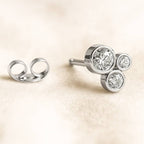 earring with three round diamonds on a beige background