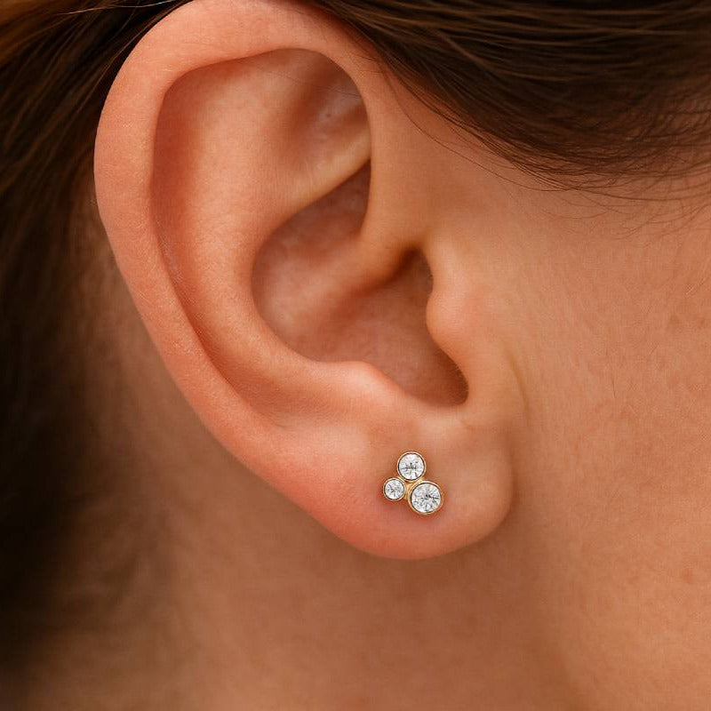 Close-up of an ear wearing 3 diamond stud earrings.