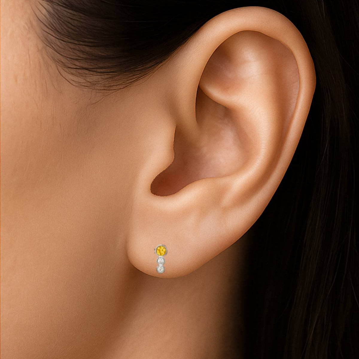 Close-up of an ear wearing a diamond earring with a dark background