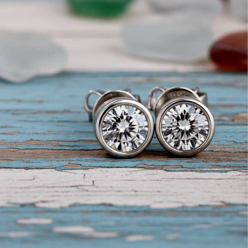 Pair of diamond stud earrings on a wood background