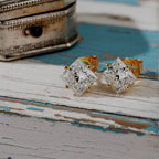 Pair of diamond earrings on a soft wood background