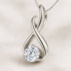 Gold infinity pendant with a diamond on a light background