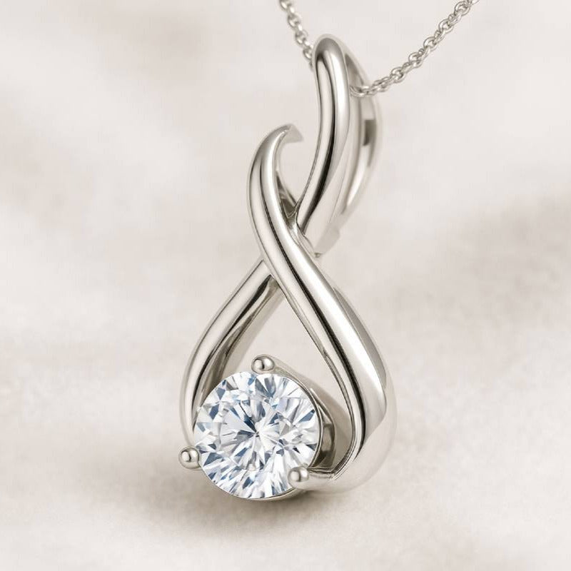 Gold infinity pendant with a diamond on a light background