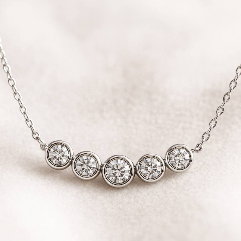 Gold necklace with five round diamonds on a light pink background